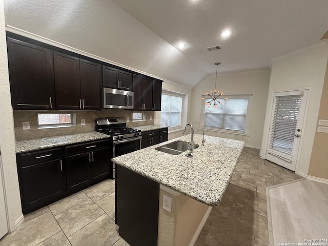 kitchen featuring sink, vaulted ceiling, decorative light fixtures, a center island with sink, and appliances with stainless steel finishes