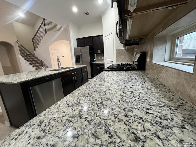 kitchen with decorative backsplash, light stone countertops, ornamental molding, stainless steel appliances, and sink