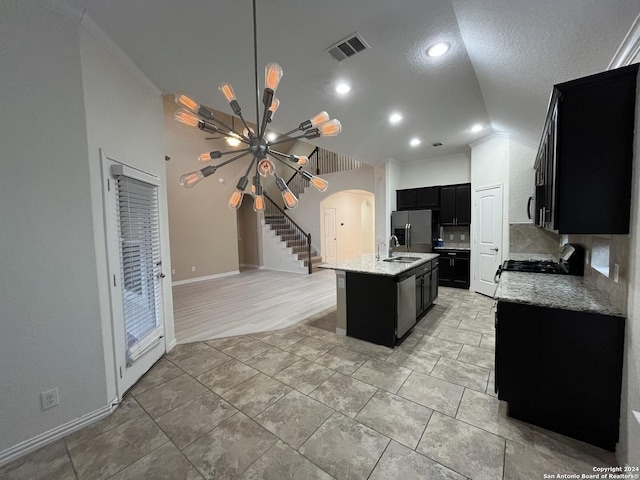 kitchen featuring appliances with stainless steel finishes, crown molding, sink, a notable chandelier, and an island with sink