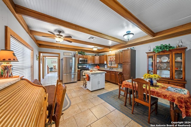 kitchen with decorative backsplash, light tile patterned floors, beamed ceiling, a kitchen island, and stainless steel appliances