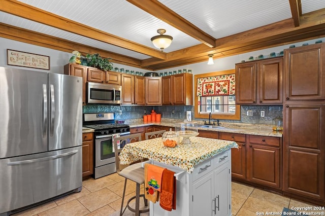 kitchen with light stone countertops, appliances with stainless steel finishes, sink, light tile patterned floors, and a kitchen island