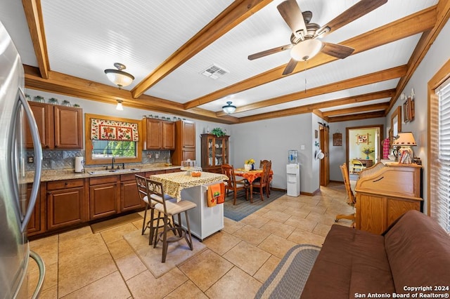 kitchen featuring decorative backsplash, stainless steel fridge, a center island, and light stone counters