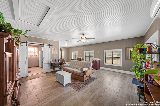 living room featuring a barn door, ceiling fan, and a wall mounted air conditioner