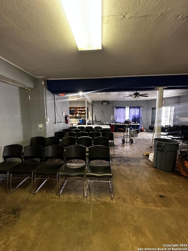 miscellaneous room featuring a textured ceiling, concrete floors, and ceiling fan