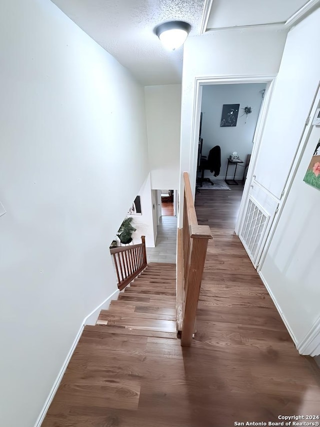 corridor with dark wood-type flooring and a textured ceiling