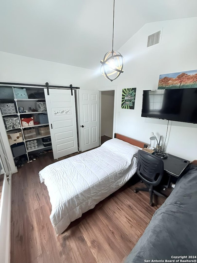 bedroom featuring a barn door, dark hardwood / wood-style flooring, and vaulted ceiling