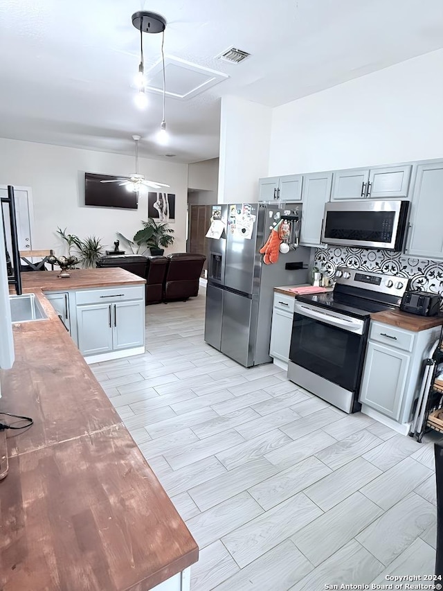 kitchen with backsplash, light hardwood / wood-style flooring, stainless steel appliances, and wood counters