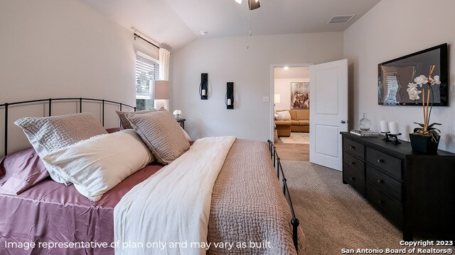 bedroom with ceiling fan, light carpet, and vaulted ceiling