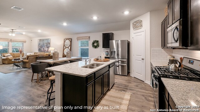 kitchen featuring a healthy amount of sunlight, sink, a kitchen island with sink, and appliances with stainless steel finishes