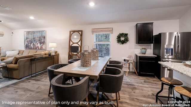 dining area featuring vaulted ceiling and light hardwood / wood-style flooring