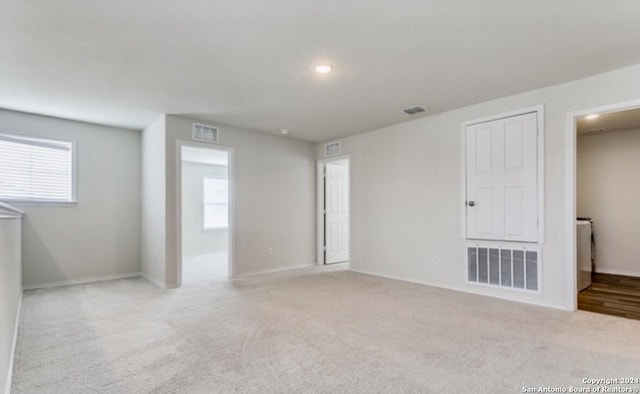 spare room featuring light colored carpet and washer / dryer