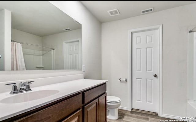 bathroom featuring a shower with curtain, hardwood / wood-style floors, vanity, and toilet