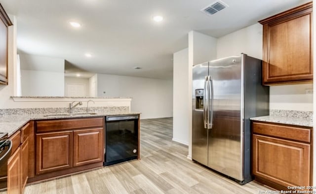 kitchen with light wood-type flooring, sink, light stone counters, and black appliances