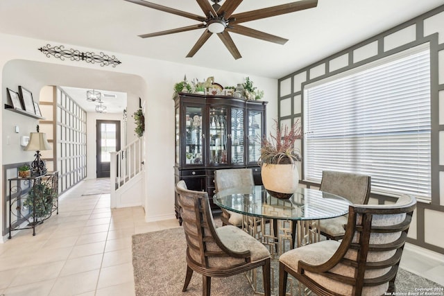 dining space featuring light tile patterned flooring and ceiling fan with notable chandelier