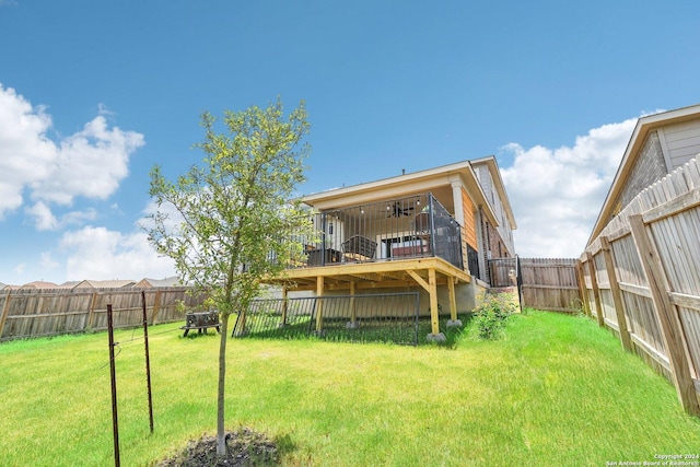 rear view of house with ceiling fan, a deck, and a yard