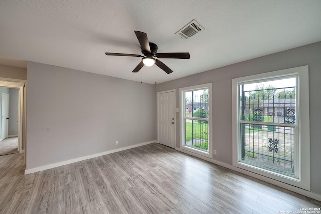 spare room with light hardwood / wood-style flooring, ceiling fan, and a healthy amount of sunlight