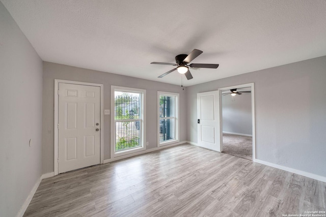 unfurnished room featuring ceiling fan, a textured ceiling, and light wood-type flooring