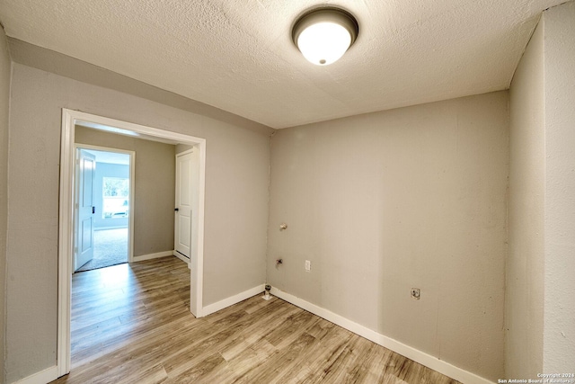 spare room with a textured ceiling and light hardwood / wood-style flooring