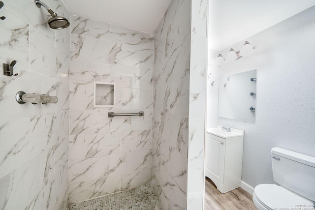 bathroom featuring a tile shower, vanity, hardwood / wood-style flooring, and toilet