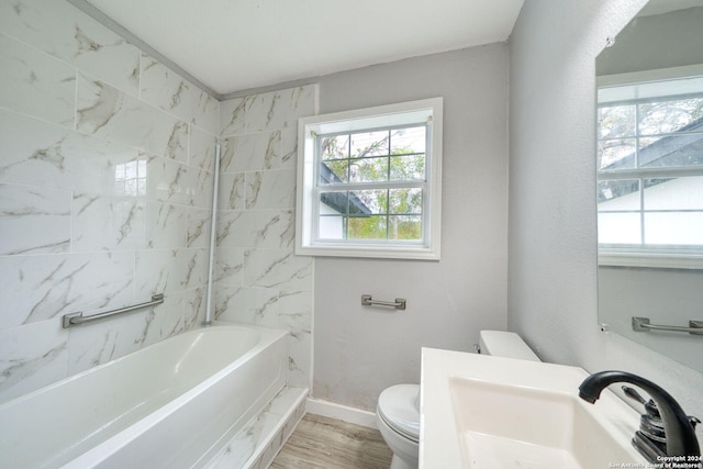 full bathroom with sink, hardwood / wood-style floors, tiled shower / bath combo, and toilet