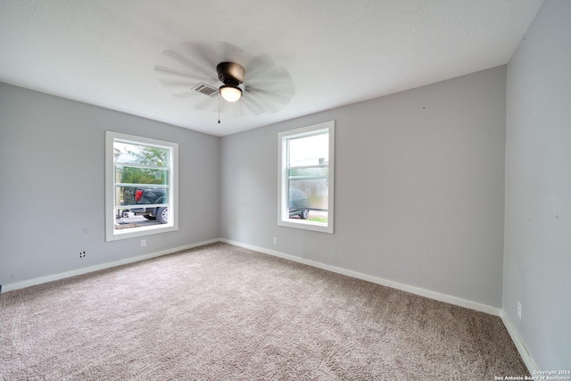 carpeted spare room featuring ceiling fan, a healthy amount of sunlight, and a textured ceiling