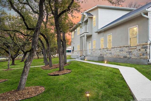 yard at dusk featuring a balcony