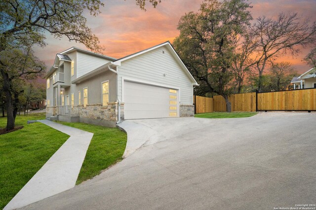 property exterior at dusk featuring a lawn and a garage