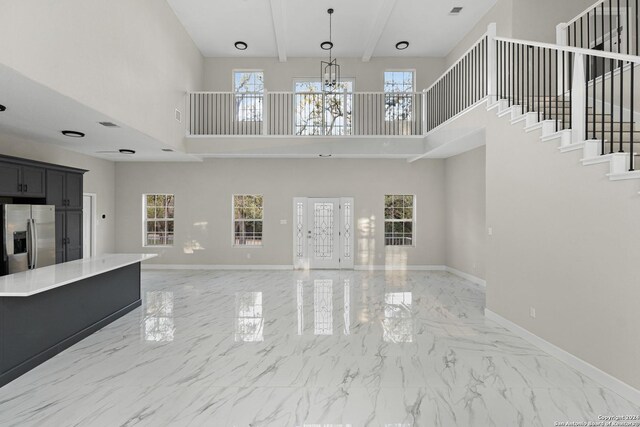 unfurnished living room with a high ceiling and an inviting chandelier