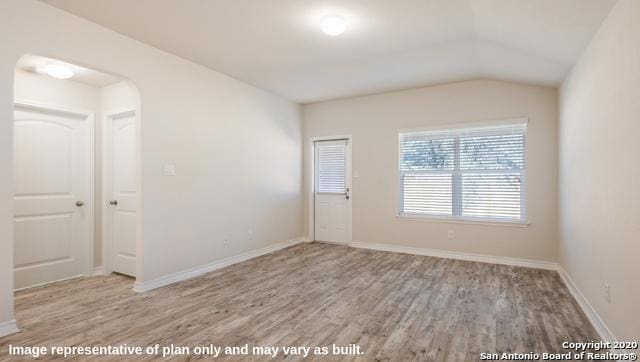 unfurnished room with vaulted ceiling and light hardwood / wood-style flooring