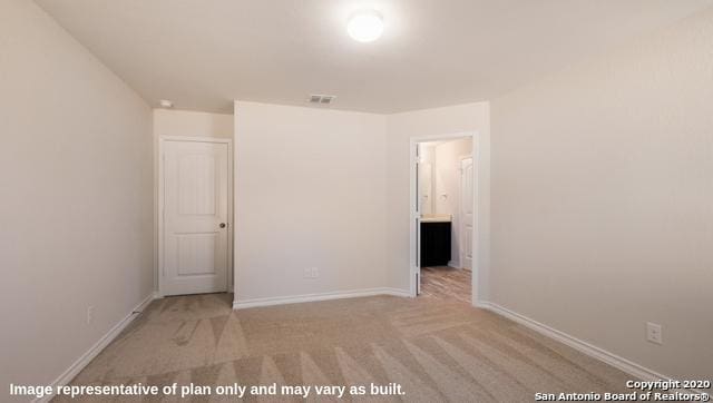 unfurnished bedroom featuring light carpet and ensuite bathroom