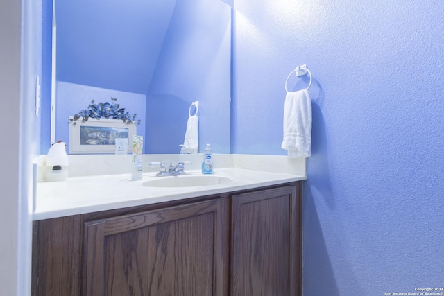 bathroom featuring vanity and lofted ceiling