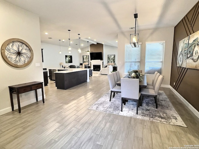 dining area featuring light wood-type flooring and vaulted ceiling