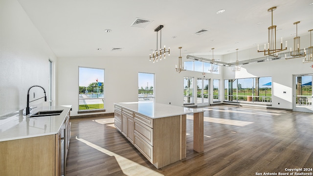 kitchen featuring a large island, light brown cabinets, sink, dark hardwood / wood-style floors, and decorative light fixtures