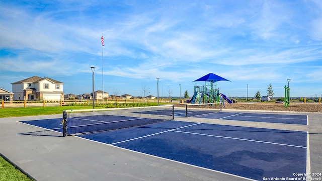 view of tennis court featuring a playground and basketball hoop