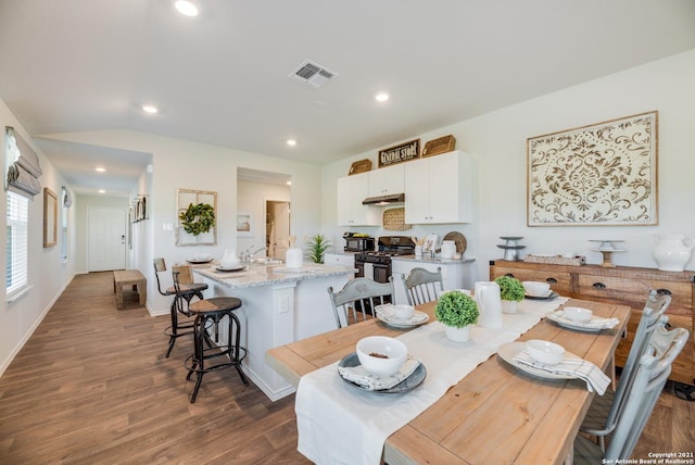 dining room featuring dark hardwood / wood-style floors, sink, and vaulted ceiling