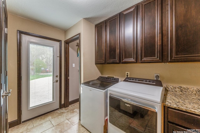 laundry area with cabinets, light tile patterned floors, a textured ceiling, and separate washer and dryer