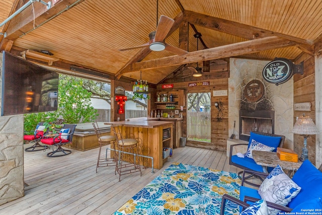 wooden terrace with a gazebo, ceiling fan, exterior bar, and an outdoor stone fireplace