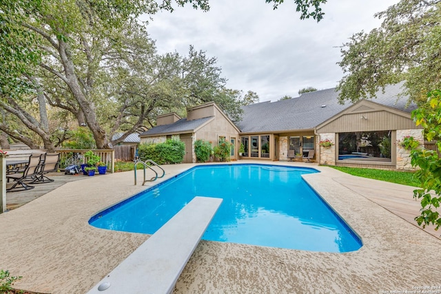 view of swimming pool with a diving board and a patio area