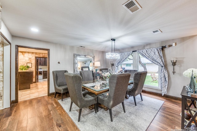 dining room with hardwood / wood-style flooring, a textured ceiling, and an inviting chandelier