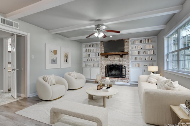 living room with beamed ceiling, ceiling fan, light hardwood / wood-style floors, and a fireplace