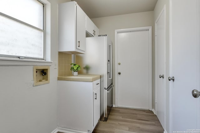 kitchen with backsplash, white cabinetry, light hardwood / wood-style flooring, and white fridge with ice dispenser