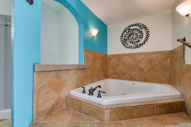 bathroom with tiled bath and tile patterned flooring