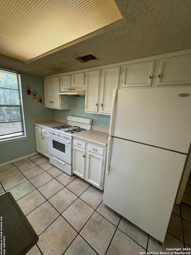 kitchen featuring white cabinetry, light tile patterned flooring, and white appliances