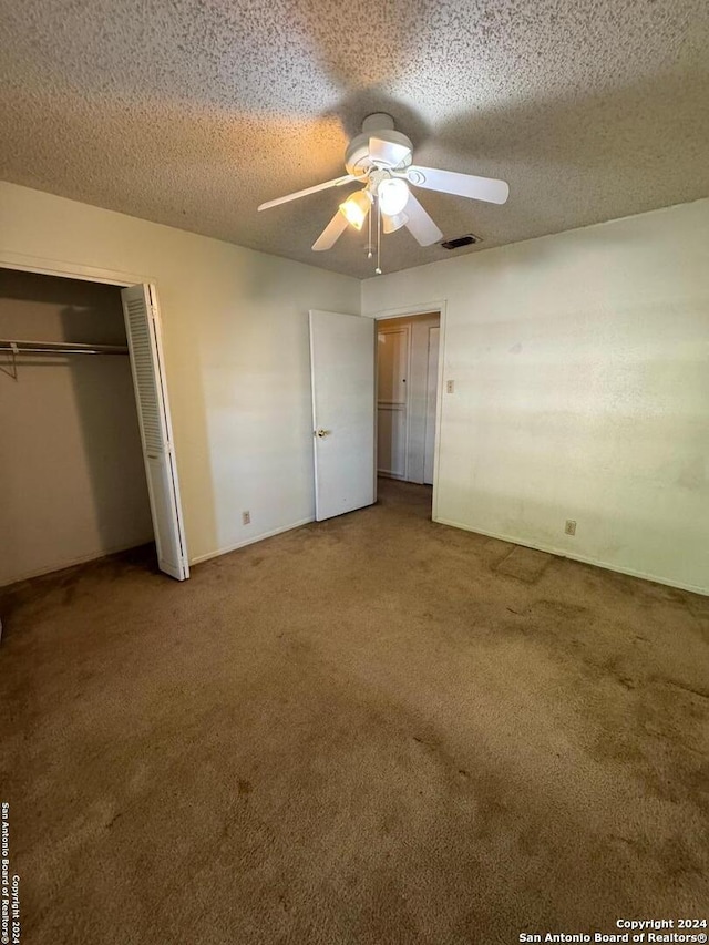 unfurnished bedroom with carpet, a textured ceiling, and ceiling fan