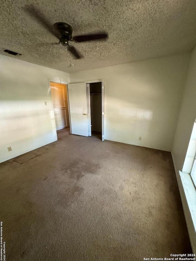 unfurnished bedroom with ceiling fan, a closet, carpet, and a textured ceiling