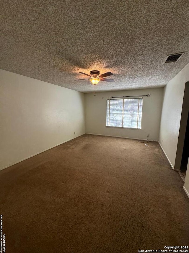 carpeted empty room with ceiling fan and a textured ceiling