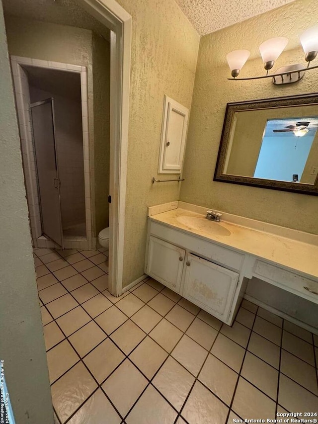 bathroom with vanity, tile patterned floors, toilet, a textured ceiling, and a shower with shower door