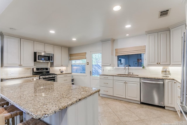 kitchen featuring sink, stainless steel appliances, white cabinets, and a breakfast bar area