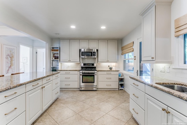 kitchen with light stone counters, appliances with stainless steel finishes, backsplash, and white cabinetry