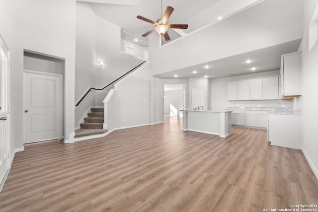 unfurnished living room featuring light hardwood / wood-style floors, high vaulted ceiling, and ceiling fan